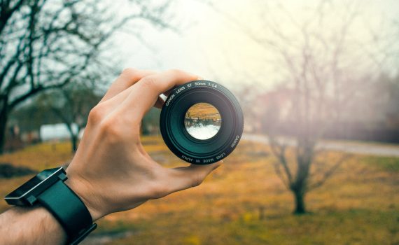 photography of person holding black camera lens